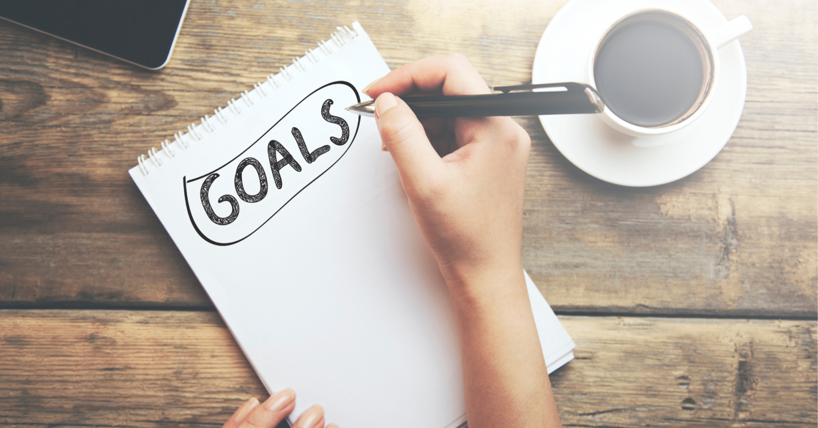 An individual comes up with ideas for New Year's resolutions by writing down their goals.